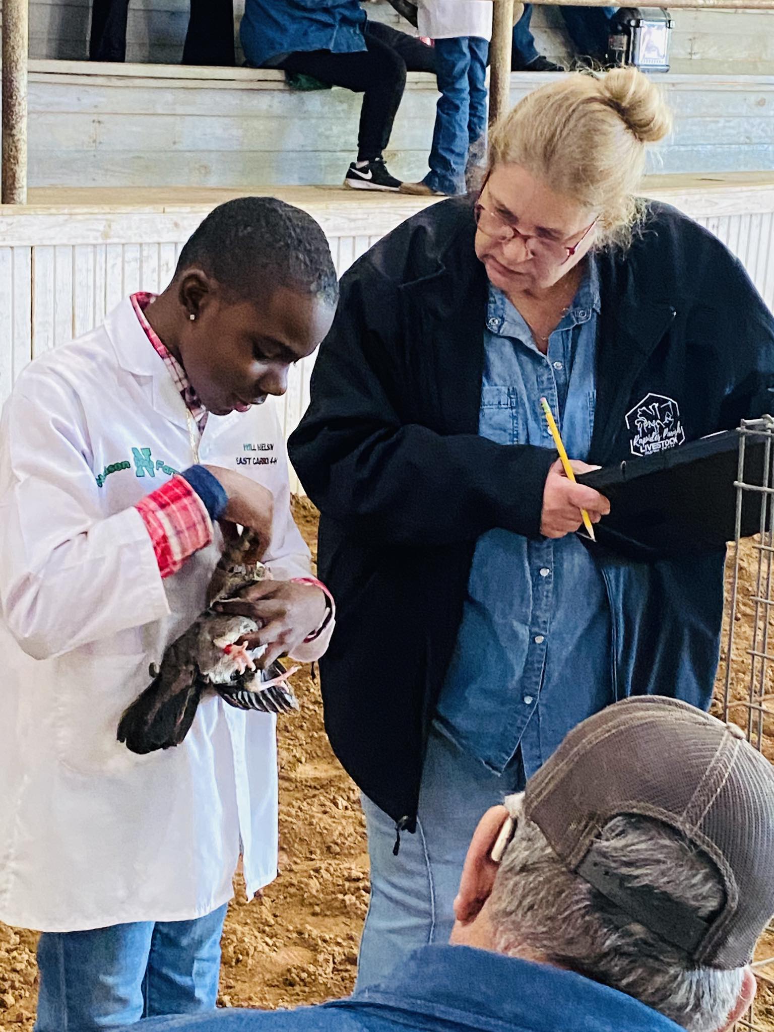 A woman looking at a boy holding a chicken.